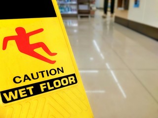 Focus on warning sign beware slippery floor and blur background of aisle inside the supermarket on...