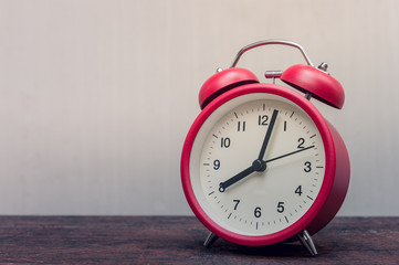 Red alarm clock on a wooden table.