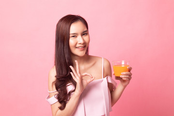 Young Asian woman show OK drink orange juice .