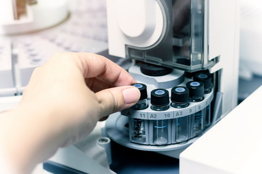 Scientist holds a chemical sample vial. People hand holding a test tube vial sets for analysis.laboratory assistant inserting laboratory glass bottle in a chromatography vial