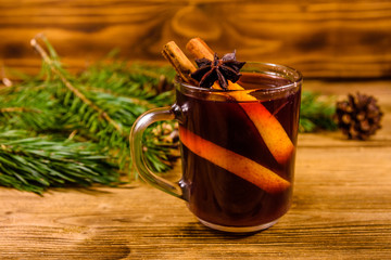 Cup of mulled wine with cinnamon and fir tree branches on wooden table