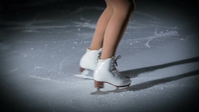 Beautiful white skates and the figure skater is spinning on the ice.