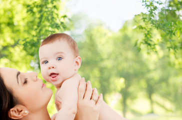 family and motherhood concept - happy smiling young mother with little baby over green natural background