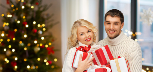 holidays and people concept - happy couple with gifts at home over christmas tree lights background