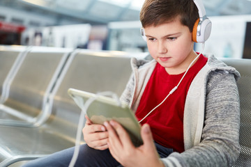 Junge mit Kopfhörer und Tablet in der Flughafen Ruhezone