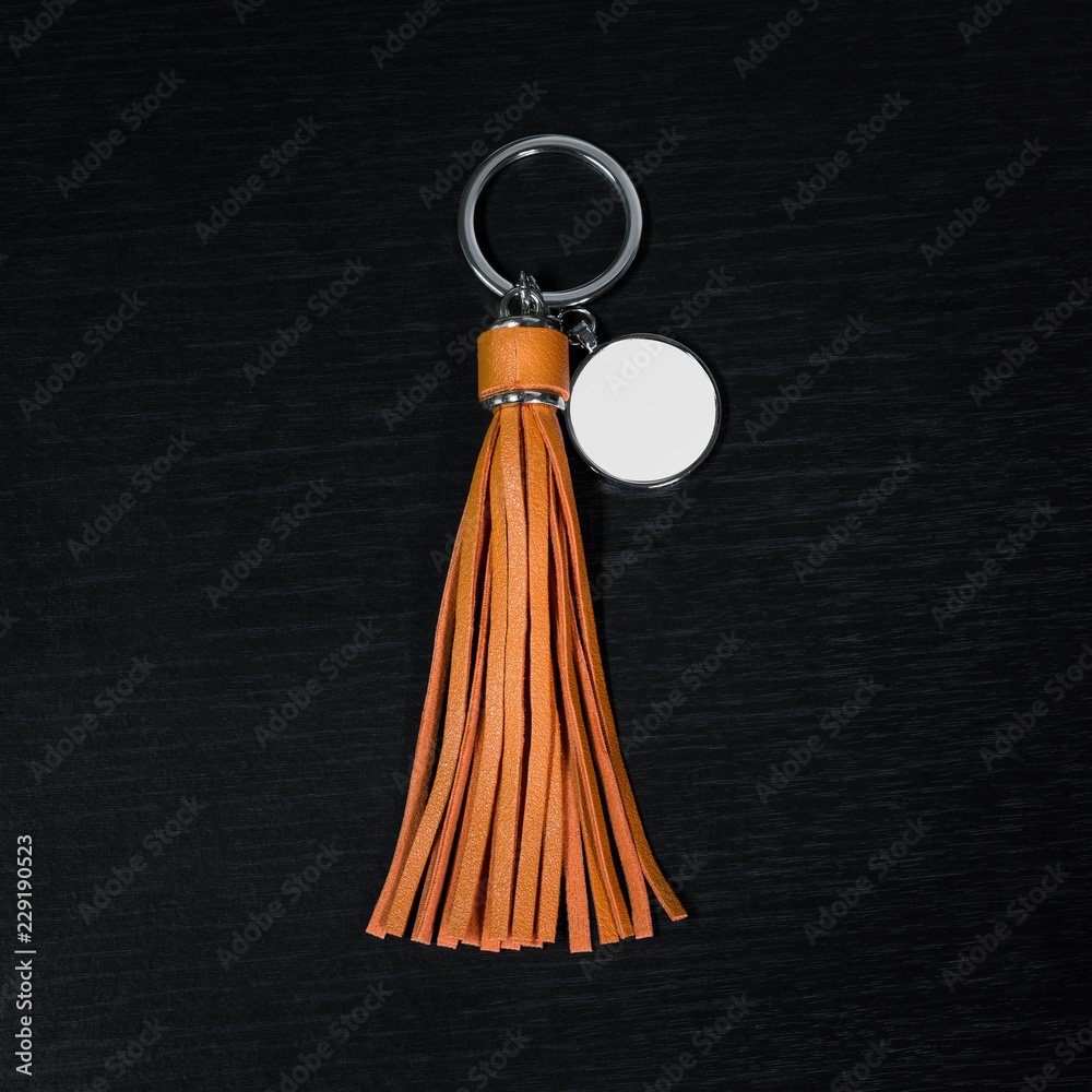 Wall mural orange leather tassel key ring on black wooden background. fashion leather key chain for decoration.