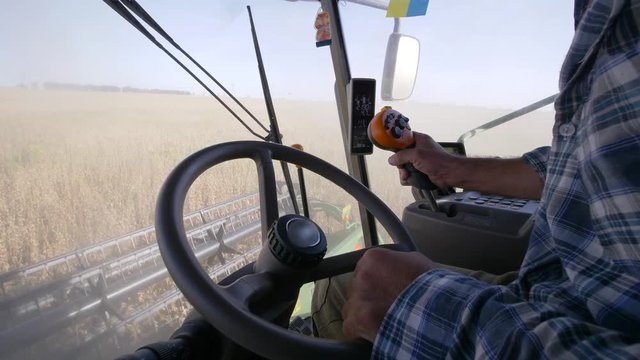 agricultural industry, elderly driver drives a large farm machinery to harvest soybeans on field in autumn season