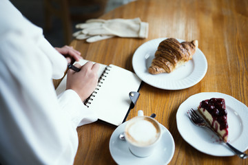 Croissant with cake with berries, chocolate spread and with cup of coffee on a marble texture background