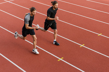 Obraz premium Two twins sportsmen brothers running at the stadium outdoors.
