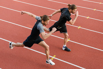 Two twins sportsmen brothers running at the stadium outdoors.