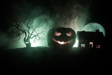 Horror view of Halloween pumpkin with scary smiling face. Head jack lantern with spooky building