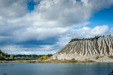 Slope of an abandoned slag heap covered ravines against the blue sky. Autumn landscape. Ruins on ex...