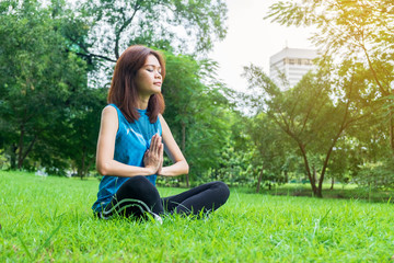 young and beautiful asian woman practicing yoga outdoors in park with green nature background. lifestyle concept.