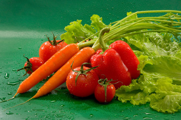 Овощи - морковь, помидоры, паприка, салат на зеленом фоне Vegetables - carrots, tomatoes, paprika, lettuce on a green background