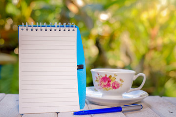 Cup of coffee, open notebook with blank pages, pen,  on green background  Still life, concept of...