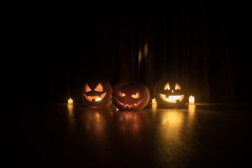 Halloween pumpkin head jack o lantern with glowing candles on background. Pumpkins on wooden floor