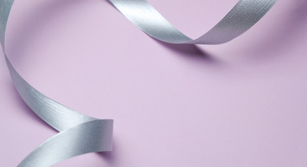 Abstract Gentle Pink Background With Silver Ribbon Curls. Minimal Style Flat Lay Copy Space
