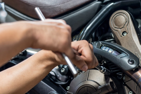 Image is Close up,People are repairing a motorcycle Use a wrench and a screwdriver to work.