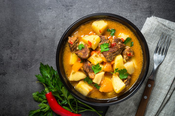 Goulash with meat and vegetables on black background. 