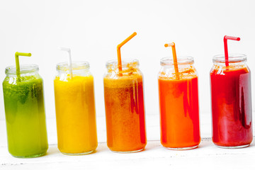 Fresh detox juices glass in row bottles on white background