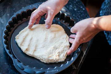 Hands putting dough into baking form. Process of preparation of apple pie. Close up, soft focus,...