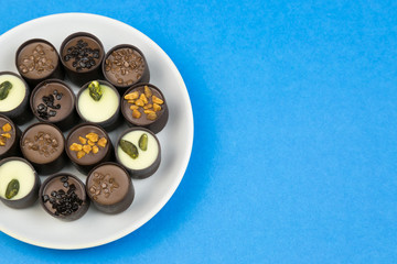 Chocolate candy on a white plate. Sweet beautiful candy lying on a plate on a bright color background.