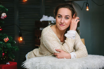 Beautiful girl in a white sweater sitting  during christmas celebration.