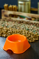 Small orange bowl for pet food and dry food as background.