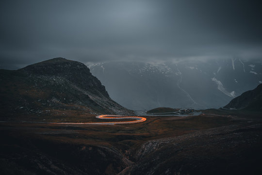 Abendstimmung mit PKW Leuchten in einer Kurve an der Grossglockner Hochalpenstrasse mit aufziehendem Nebel im Hintergrund 