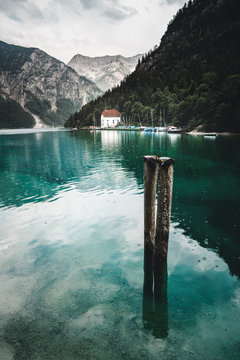 Plansee mit zwei Anlegepfosten im Wasser mit blick auf die Kapelle und den trioler Alpen