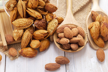 Almonds in a black bowl against dark rustic wooden background