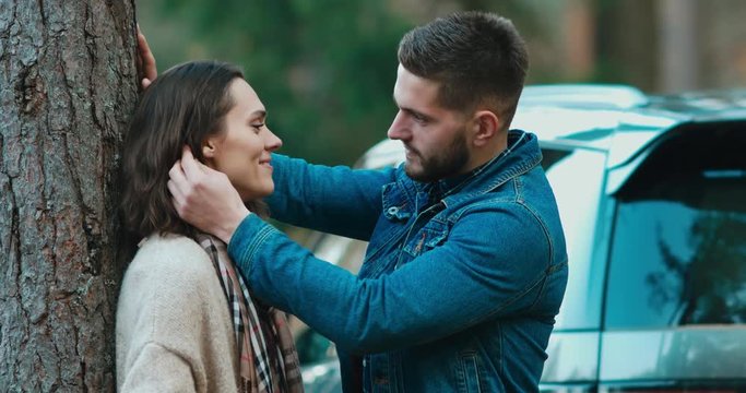 Mid 30s couple or family in love the beautiful nature, blurred modern car SUV in the background. 4K UHD 60 FPS SLOW MOTION