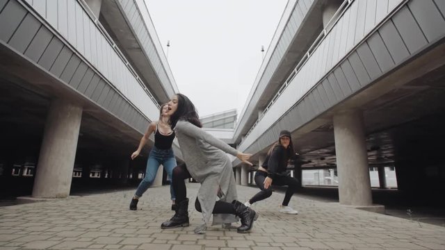 Girls in different styles of clothing dancing and performs modern hip hop dance in parking lot, posing, contemporary freestyle, industrial urban environment