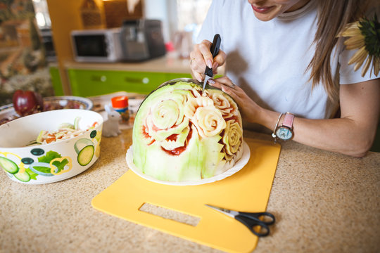 A young girl carving watermelon in her beautiful kitchen. Photo hobby