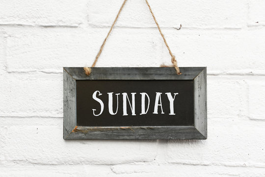Hello sunday weekend text on hanging board white brick outdoor wall