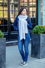 Young girl in jeans and a jacket and a scarf. Concept of lifestyle, fashion, urban