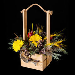 Flowers bouquet arrangement in pine basket on black background.