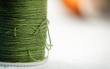 The blurred roll of green thread on background,needlework,craft,sewing and tailoring concept