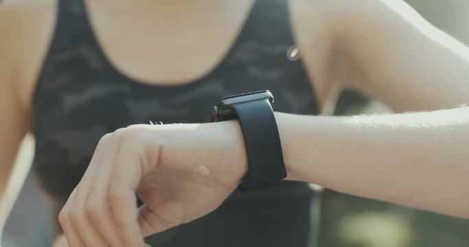 Woman using her smartwatch touchscreen wearable technology device in morning lights