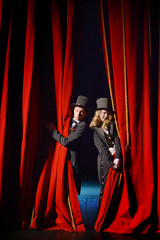 Actor and actress in tuxedos close the theater curtain