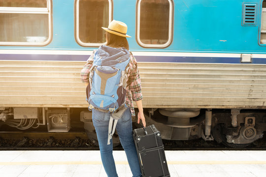 Asia woman Traveller walking and Towing the luggage over the motion blurred of train running at the train station, Travel and lifestyle concept