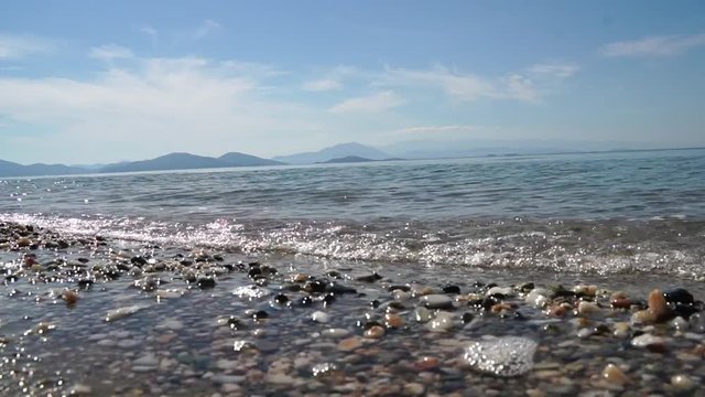 Sanfte Wellen pl&auml;tschern an den Kiesel-Strand der Meeres-K&uuml;ste