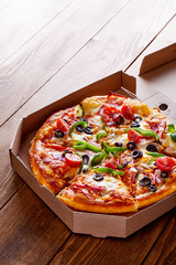 Pizza in a cardboard box on a wooden table viewed from above. Pizza delivery concept. Top view © virtustudio