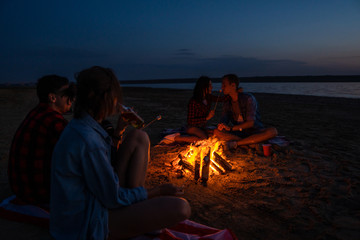 Camp on the beach. Group of young couples having picnic with bonfire