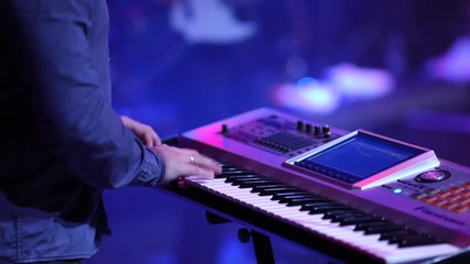 Concert rock band performing on stage. Keyboard player plays synthesizer. Slow motion