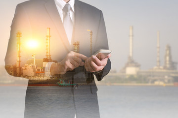 Double exposure of businessman hold and touch screen smartphone, mobile, oil fuel, Electric generating factory or plant and sunset as business, technology, communication, industrial and energy concept