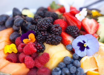 Macro image of a fruit and berry plate with edible lowers in soft focus
