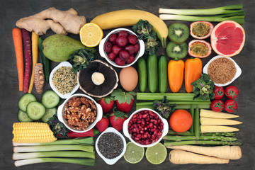 Super food concept for good health with fresh fruit and vegetables, dairy, spices, nuts and seeds with foods high in antioxidants, anthocyanins, dietary fibre and vitamins.  