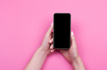 Top view of a woman hand using phone on pink background.