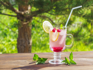 Refreshing summer cocktail with lemon, raspberry and mint a wooden table